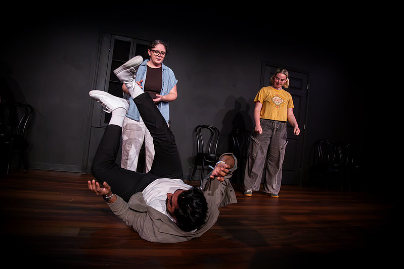 Parimal mid-scene on stage during an improv performance, being lifted by a scene partner while two other performers react